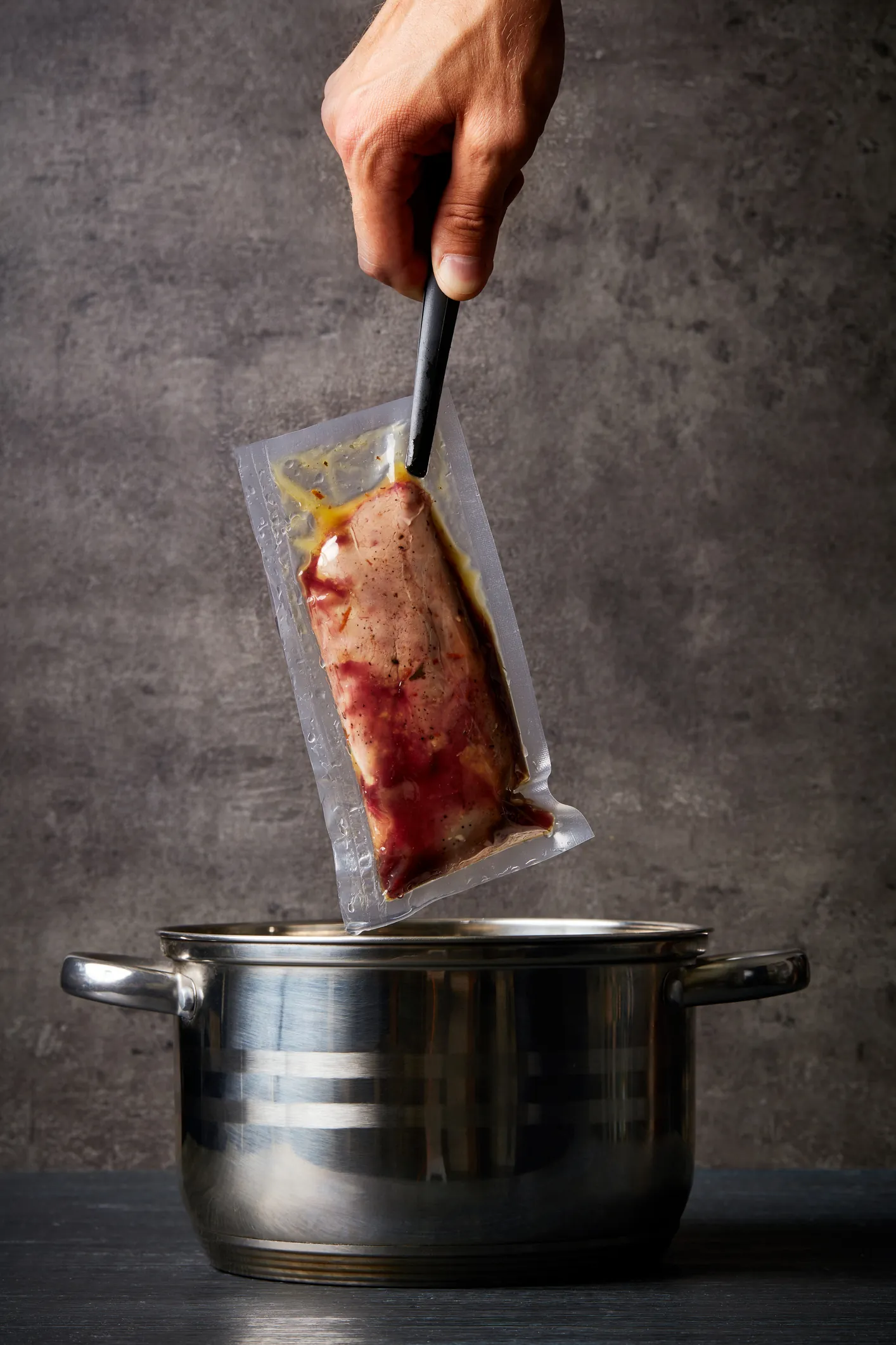Vacuümzak met vlees sous-vide boven een kookpot — kook- en retortzak